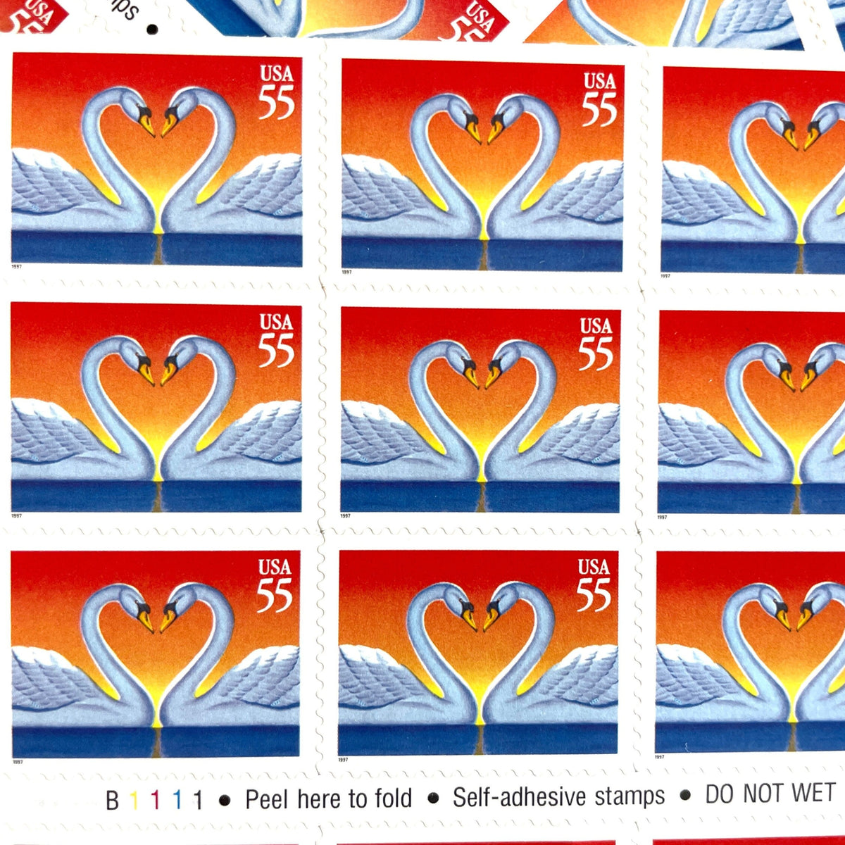 Love Swans postage stamps from 1997 featuring two white swans facing one another with their curved necks forming a heart on vintage unused 55-cent USPS postage, Scott 3124.