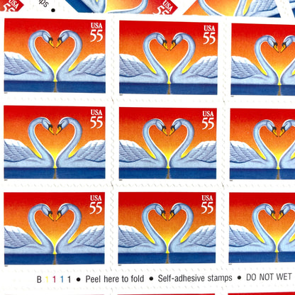 Love Swans postage stamps from 1997 featuring two white swans facing one another with their curved necks forming a heart on vintage unused 55-cent USPS postage, Scott 3124.