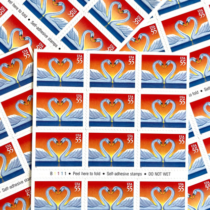 Love Swans postage stamps from 1997 featuring two white swans facing one another with their curved necks forming a heart on vintage unused 55-cent USPS postage, Scott 3124.