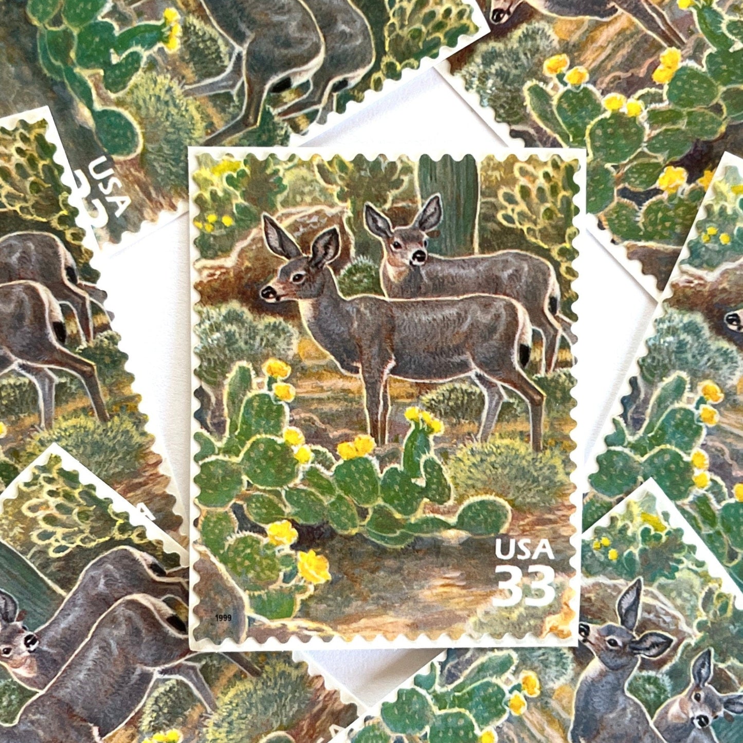 Image of Desert Mule Deer postage stamps from the 1999 Nature of America Sonoran Desert series, featuring brown mule deer standing amongst green cactus with yellow flowers in a Southwestern desert landscape on vintage unused 33-cent USPS postage, Scott 3293f.