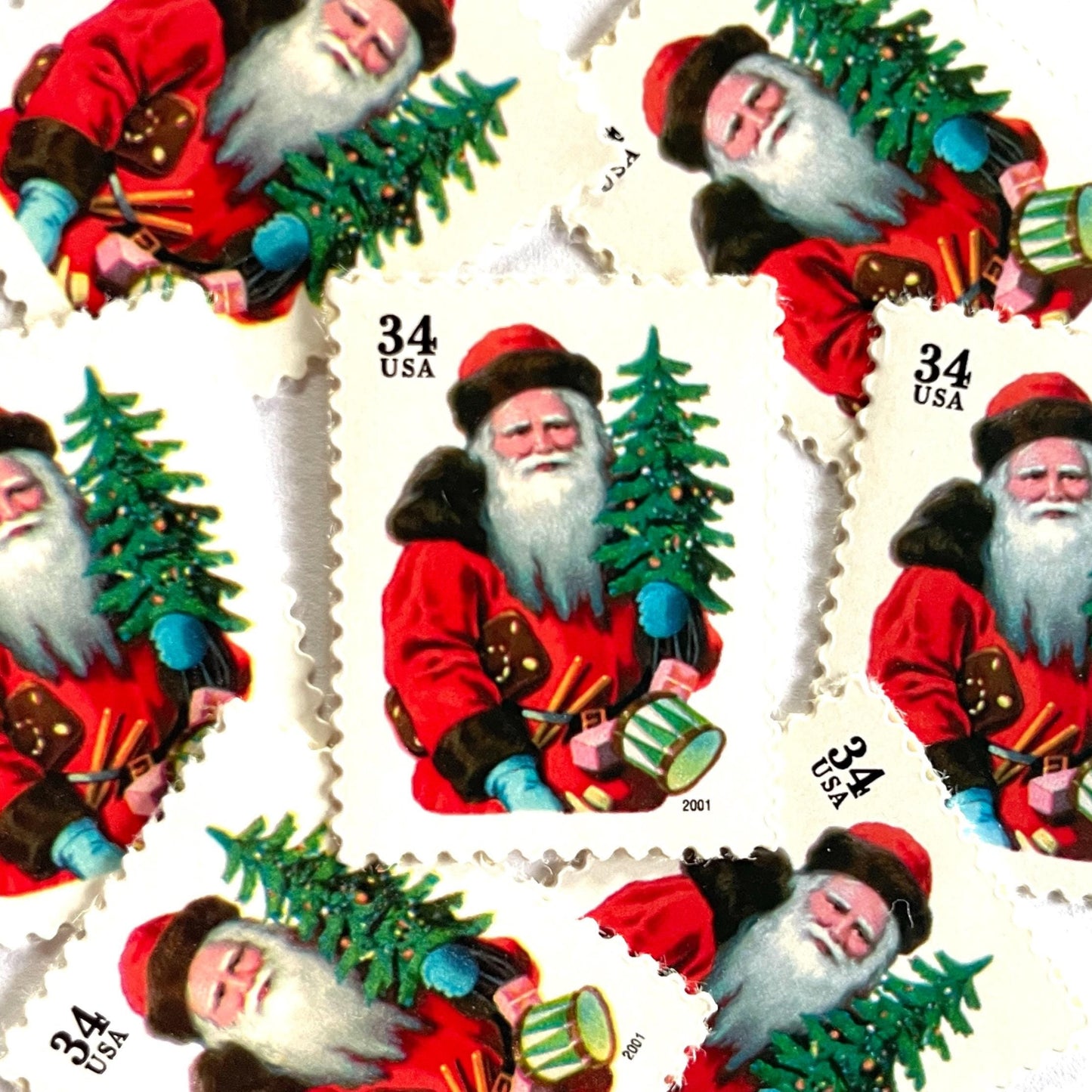 Image of 34-cent Contemporary Christmas 2001 Santa Claus Se-tenant "Santa with Red Hat" and Christmas Tree USPS postage stamp featuring a portly and jovial Santa holding a Christmas tree, with a full white beard and a warm, inviting smile, gazing directly out from the stamp. He is wearing a red suit trimmed with brown fur, and a red cap. Scott #3539. Stamp themes: Christmas, holidays, winter, Santa Claus, toys, gifts, winter wedding, winter save-the-date. Red postage stamp.