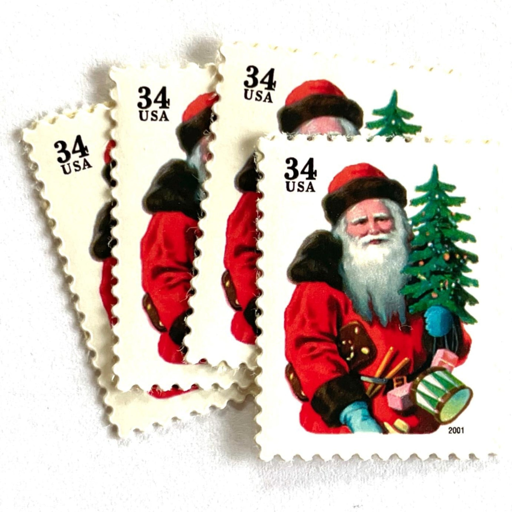 Image of 34-cent Contemporary Christmas 2001 Santa Claus Se-tenant "Santa with Red Hat" and Christmas Tree USPS postage stamps featuring a portly and jovial Santa holding a Christmas tree, with a full white beard and a warm, inviting smile, gazing directly out from the stamp. He is wearing a red suit trimmed with brown fur, and a red cap. Scott #3539. Stamp themes: Christmas, holidays, winter, Santa Claus, toys, gifts, winter wedding, winter save-the-date. Red postage stamp.