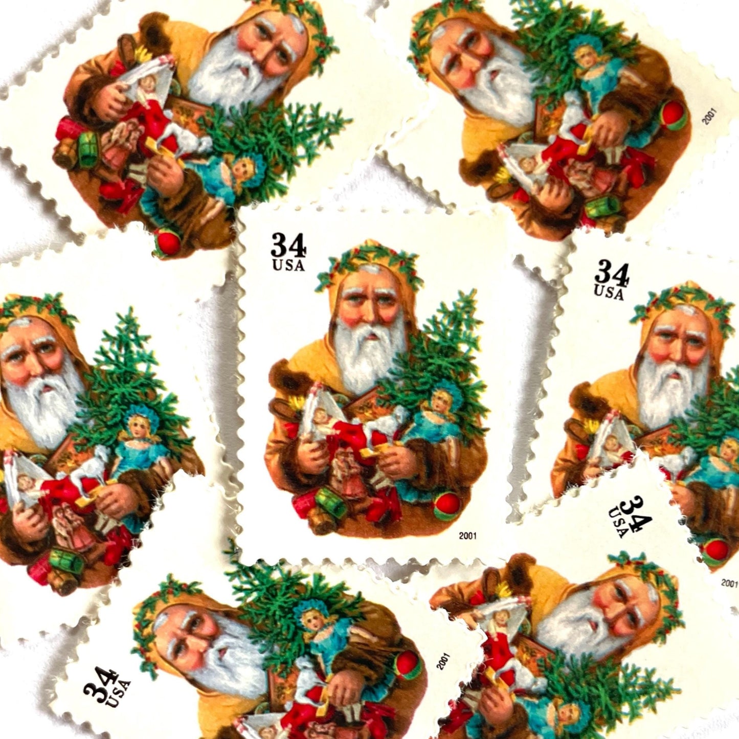 Image of 34-cent Contemporary Christmas 2001 Santa Claus Se-tenant "Santa with Dog” and Christmas Tree USPS postage stamp featuring an “old world" bearded Santa Claus shown in a long, brown, fur-trimmed robe with a hood. He wears a crown of green leaves or holly and holds an open book in one hand. He carries several traditional toys, including a toy dog, a doll, and a small Christmas tree. Scott #3540. Stamp themes: Christmas, holidays, winter, Santa Claus, toys, gifts, winter wedding, winter save-the-date.