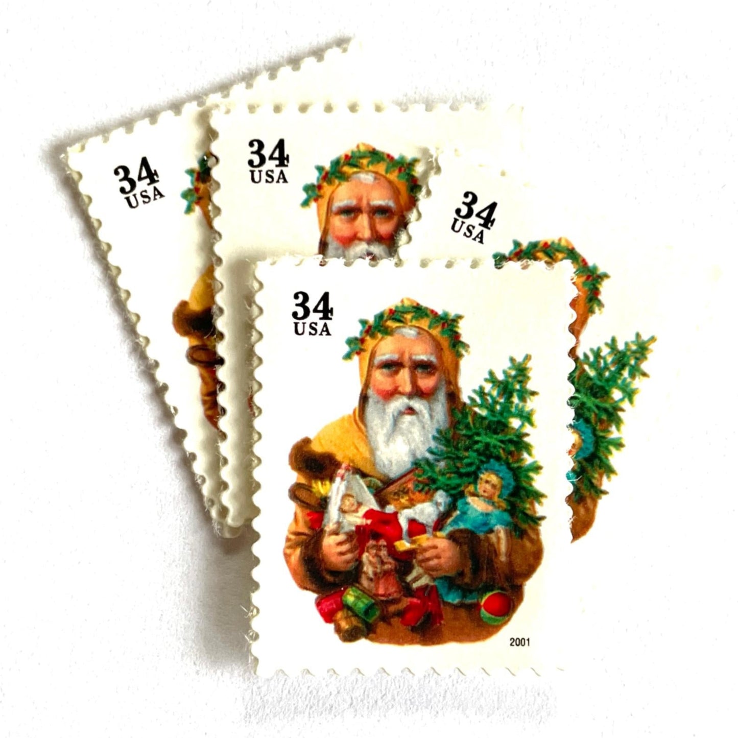 Image of 34-cent Contemporary Christmas 2001 Santa Claus Se-tenant "Santa with Dog” and Christmas Tree USPS postage stamp featuring an “old world" bearded Santa Claus shown in a long, brown, fur-trimmed robe with a hood. He wears a crown of green leaves or holly and holds an open book in one hand. He carries several traditional toys, including a toy dog, a doll, and a small Christmas tree. Scott #3540. Stamp themes: Christmas, holidays, winter, Santa Claus, toys, gifts, winter wedding, winter save-the-date.