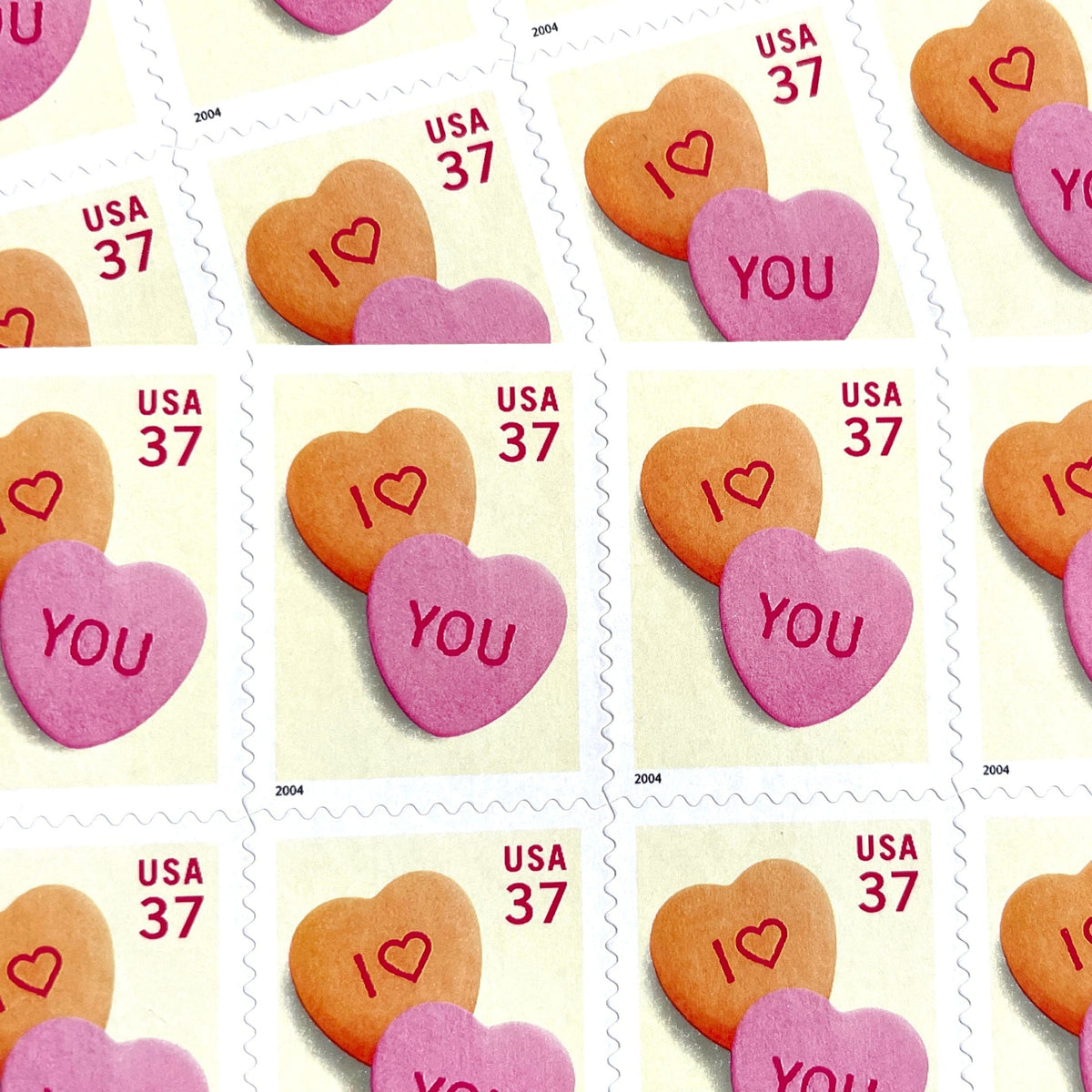 Candy Hearts postage stamps from 2004 featuring pink and yellow conversation hearts spelling I love you on vintage unused 37-cent USPS postage, Scott 3833.