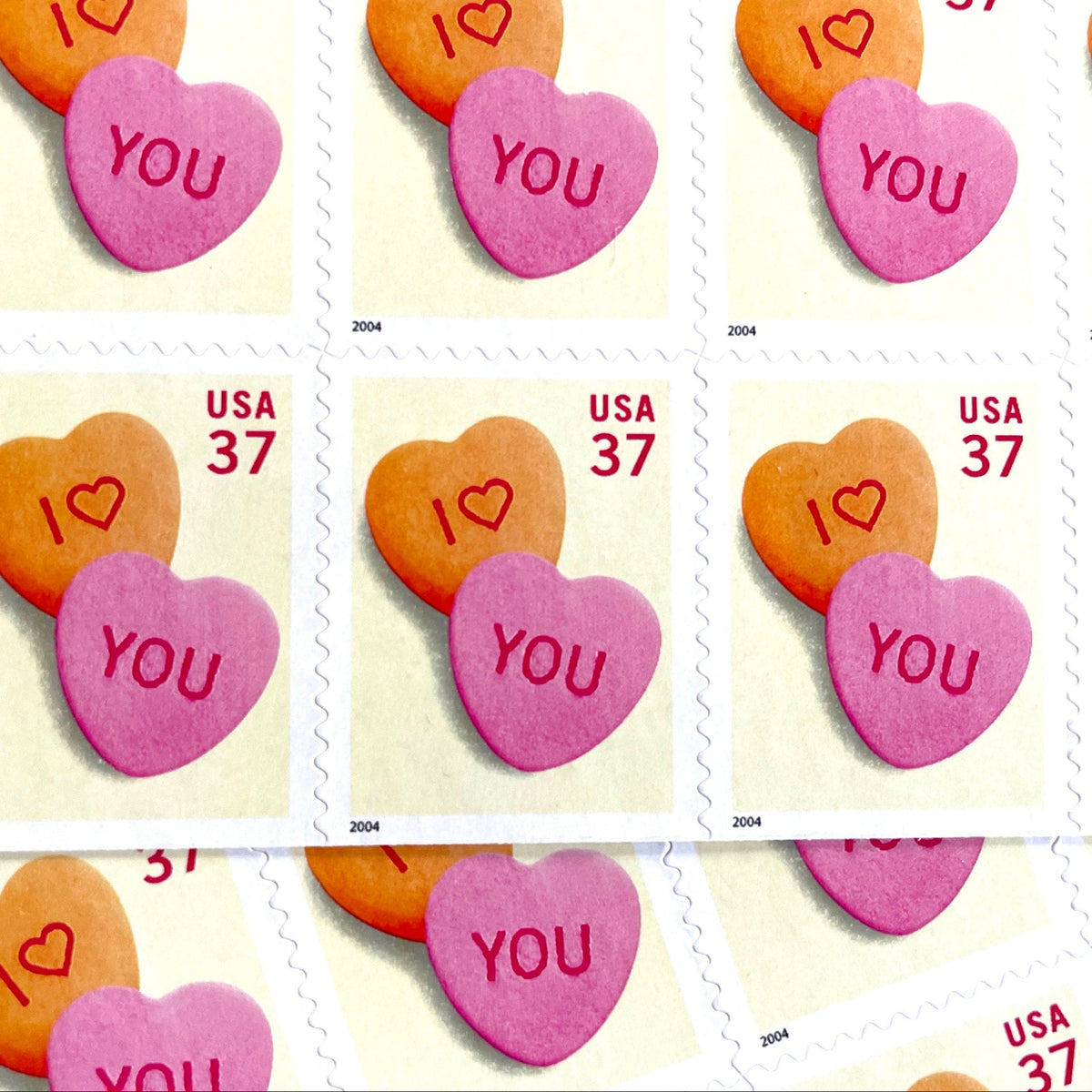Candy Hearts postage stamps from 2004 featuring pink and yellow conversation hearts spelling I love you on vintage unused 37-cent USPS postage, Scott 3833.