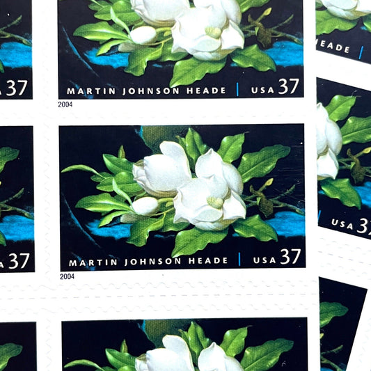 Image of 2004 American Treasures series “Martin Johnson Heade Painting” ("Giant Magnolias on a Blue Velvet Cloth”) unused 37-cent vintage USPS mail stamps. Scott #3872. Stamp Themes: Flowers, White Flowers, Floral, Botanical, Gardening, American Trees, Magnolia Tree, Magnolia Flowers. Dark Blue, Black, White, Green, Multicolored self-adhesive postage stamp. Perfect postage stamp to use for save the date announcements, wedding invitation postage, bridal shower invitations, birth announcements, thank you card
