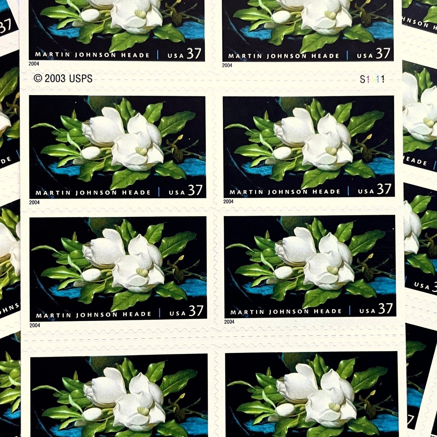 Image of 2004 American Treasures series “Martin Johnson Heade Painting” ("Giant Magnolias on a Blue Velvet Cloth”) unused 37-cent vintage USPS mail stamps. Scott #3872. Stamp Themes: Flowers, White Flowers, Floral, Botanical, Gardening, American Trees, Magnolia Tree, Magnolia Flowers. Dark Blue, Black, White, Green, Multicolored self-adhesive postage stamp. Perfect postage stamp to use for save the date announcements, wedding invitation postage, bridal shower invitations, birth announcements, thank you card