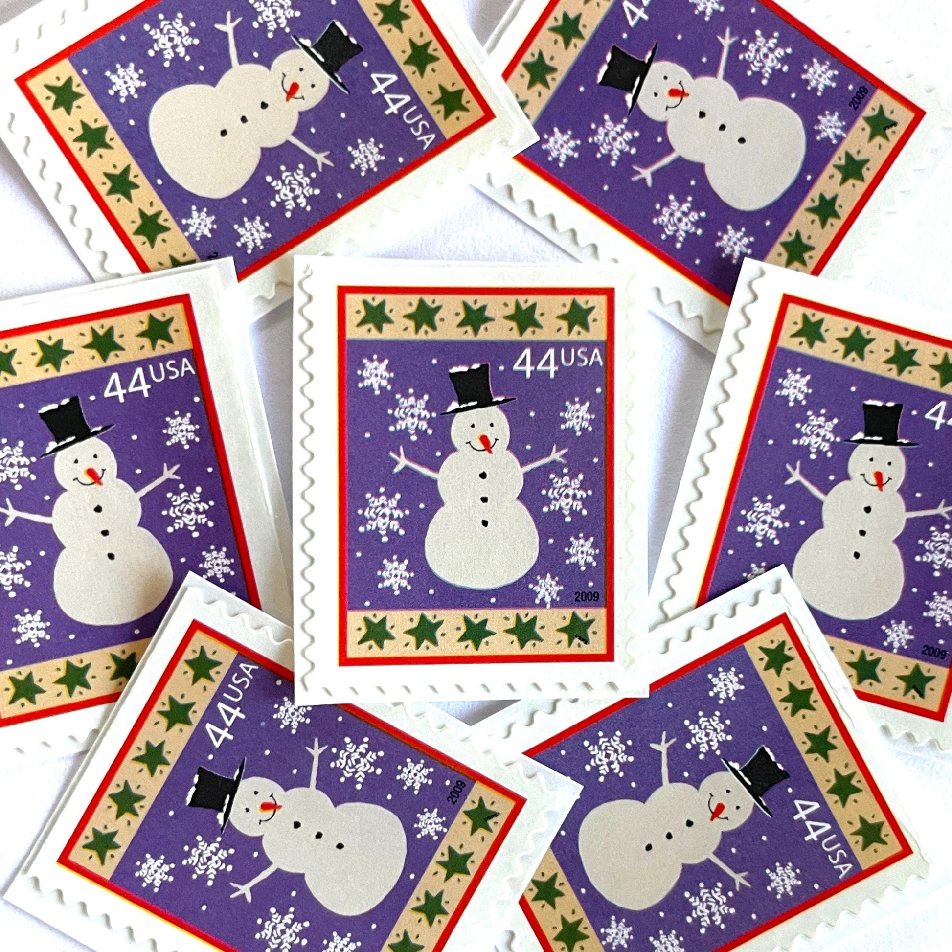 Image of 44-cent Contemporary Christmas Winter Holidays Snowman USPS postage stamp featuring a white snowman and snowflakes against a purple background with a design reminiscent of Christmas wrapping paper. Scott #4426. Stamp themes: Christmas, holidays, winter, snow, snowflakes, winter wedding, winter save-the-date. Purple postage stamp.