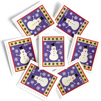 Image of 44-cent Contemporary Christmas Winter Holidays Snowman USPS postage stamps featuring a white snowman and snowflakes against a purple background with a design reminiscent of Christmas wrapping paper. Scott #4426. Stamp themes: Christmas, holidays, winter, snow, snowflakes, winter wedding, winter save-the-date. Purple postage stamp.