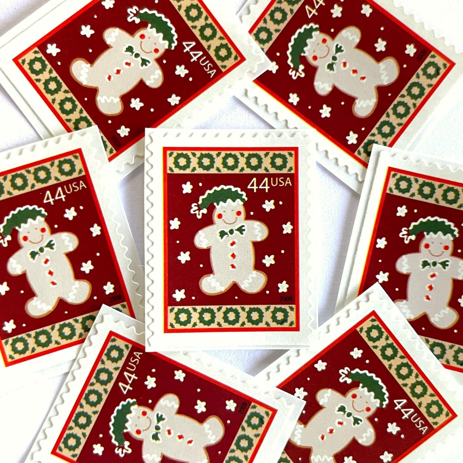 Image of 44-cent Contemporary Christmas Winter Holidays Gingerbread Man USPS postage stamp featuring a beige gingerbread man and snowflakes against a red background with a design reminiscent of Christmas wrapping paper. Scott #4427. Stamp themes: Christmas, holidays, winter, snowflakes, baking, icing, cookies, winter wedding, winter save-the-date. Red postage stamp.