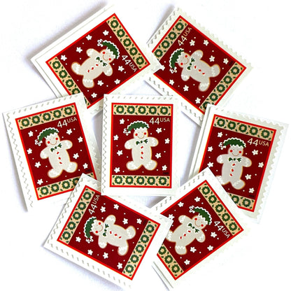Image of 44-cent Contemporary Christmas Winter Holidays Gingerbread Man USPS postage stamps featuring a beige gingerbread man and snowflakes against a red background with a design reminiscent of Christmas wrapping paper. Scott #4427. Stamp themes: Christmas, holidays, winter, snowflakes, baking, icing, cookies, winter wedding, winter save-the-date. Red postage stamp.