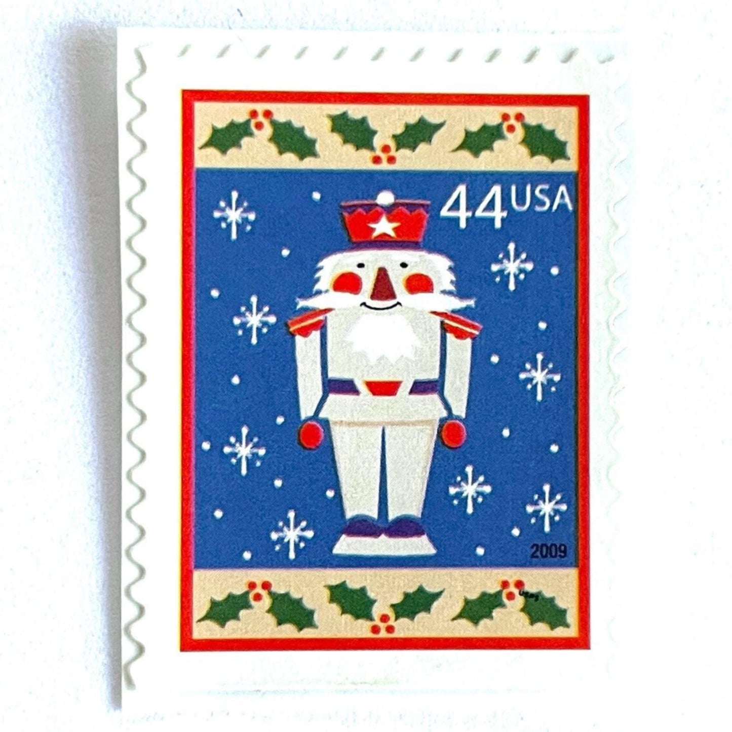 Image of 44-cent Contemporary Christmas Winter Holidays Toy Soldier USPS postage stamp featuring a smiling toy soldier standing at attention, set against a blue background with white snowflakes falling, evoking the imagery of classic holiday stories like “The Nutcracker,” with a design reminiscent of Christmas wrapping paper. Scott #4428. Stamp themes: Christmas, holidays, winter, snowflakes, toys, wooden toys, nutcracker, German, winter wedding, winter save-the-date. Blue postage stamp.