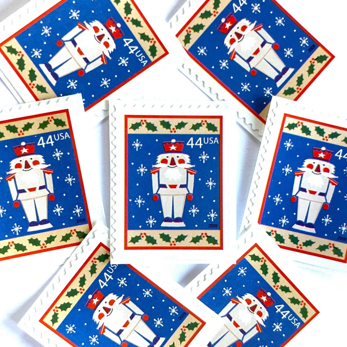 Image of 44-cent Contemporary Christmas Winter Holidays Toy Soldier USPS postage stamp featuring a smiling toy soldier standing at attention, set against a blue background with white snowflakes falling, evoking the imagery of classic holiday stories like “The Nutcracker,” with a design reminiscent of Christmas wrapping paper. Scott #4428. Stamp themes: Christmas, holidays, winter, snowflakes, toys, wooden toys, nutcracker, German, winter wedding, winter save-the-date. Blue postage stamp.