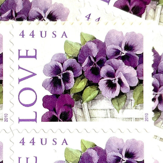 Pansies in a Basket postage stamp from 2010 featuring purple pansies and green foliage in a white woven cart on vintage unused 44-cent USPS postage, Scott 4450.
