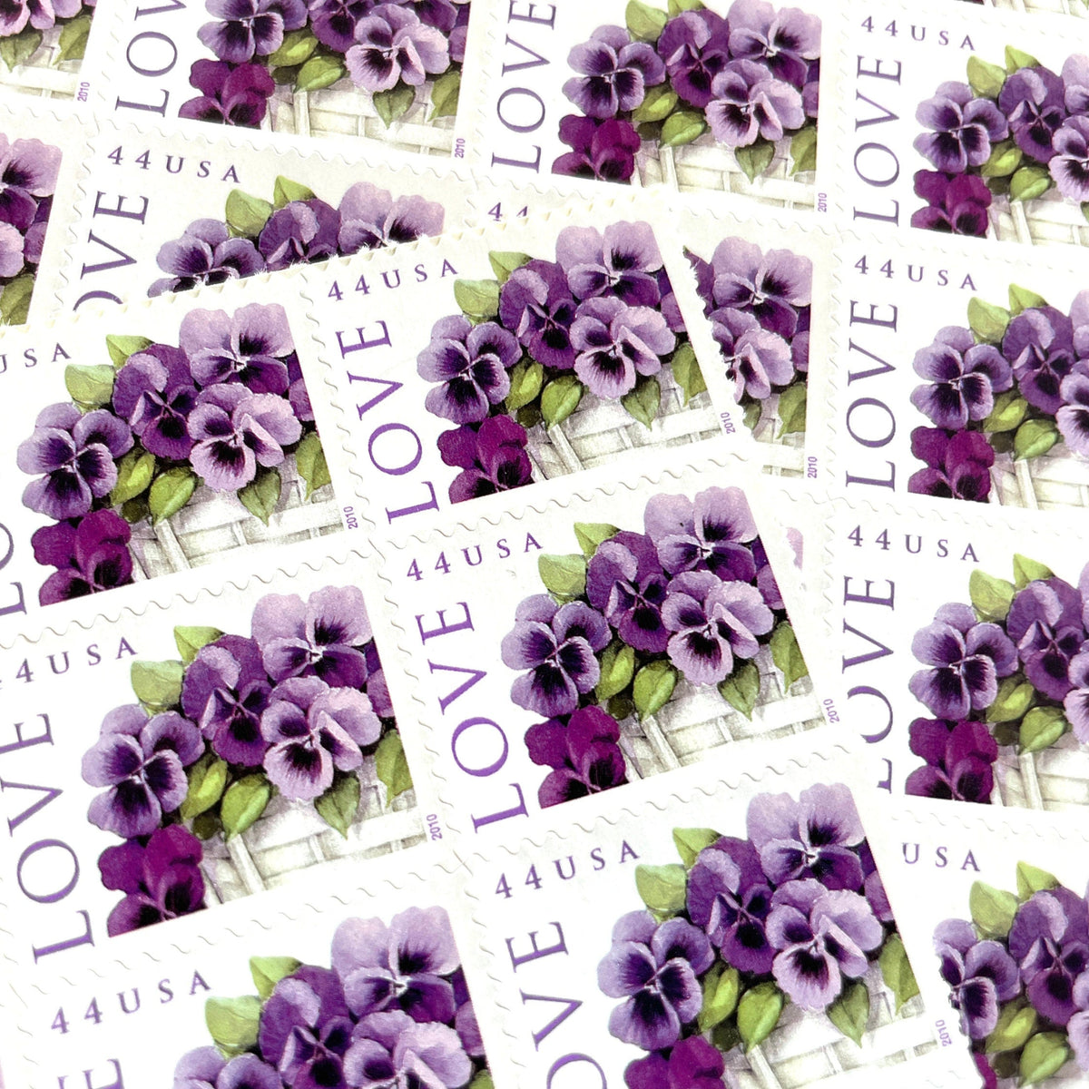 Pansies in a Basket postage stamps from 2010 featuring purple pansies and green foliage in a white woven cart on vintage unused 44-cent USPS postage, Scott 4450.