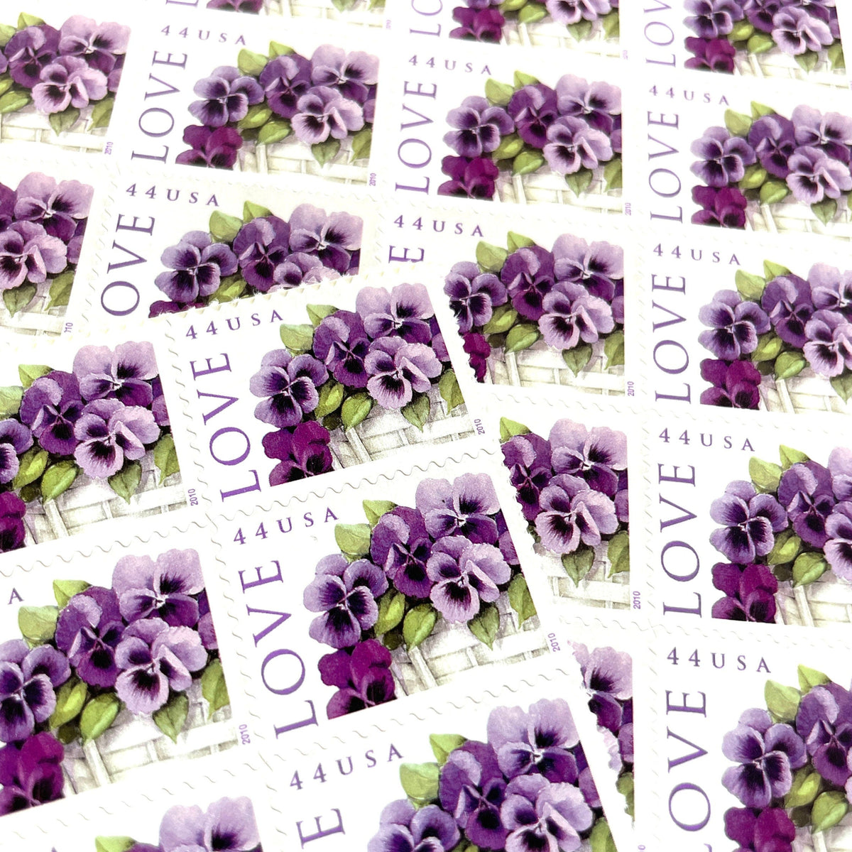 Pansies in a Basket postage stamps from 2010 featuring purple pansies and green foliage in a white woven cart on vintage unused 44-cent USPS postage, Scott 4450.