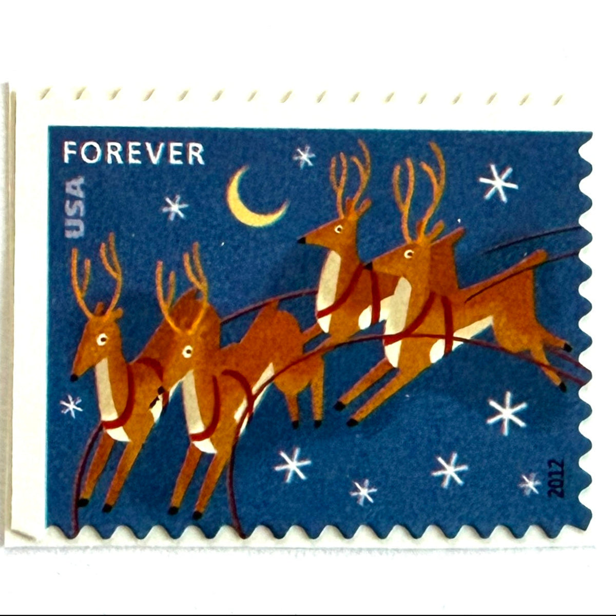 Reindeer in Flight and Moon postage stamp from 2012 featuring flying Christmas reindeer beside a glowing moon in a wintry night sky on unused USPS Forever postage, Scott 4712.