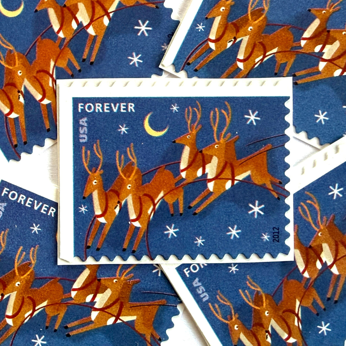 Reindeer in Flight and Moon postage stamps from 2012 featuring flying Christmas reindeer beside a glowing moon in a wintry night sky on unused USPS Forever postage, Scott 4712.