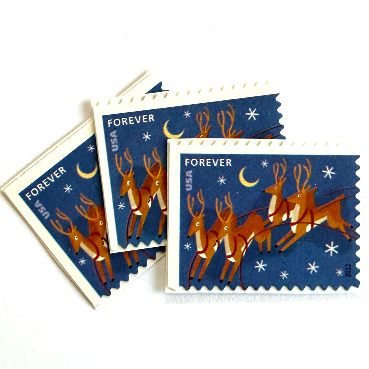 Reindeer in Flight and Moon postage stamps from 2012 featuring flying Christmas reindeer beside a glowing moon in a wintry night sky on unused USPS Forever postage, Scott 4712.