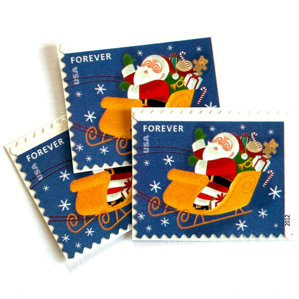 Santa Flying in Sleigh postage stamps from 2012 featuring St. Nick traveling through a wintry Christmas Eve sky in his sleigh on unused USPS Forever postage, Scott 4713.