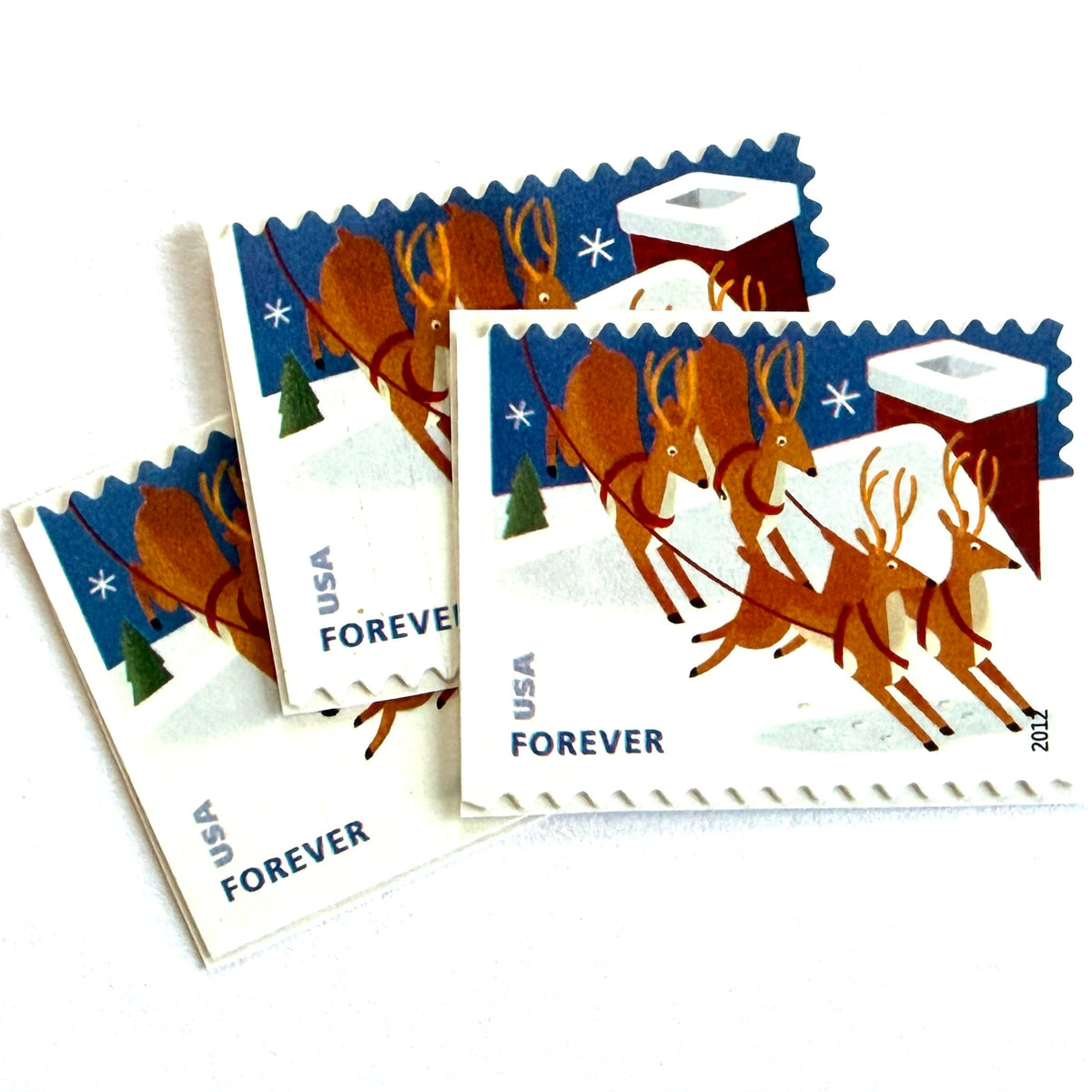 Reindeer Over Roof postage stamps from 2012 featuring flying Christmas reindeer above snow-covered rooftops in a wintry night scene on unused USPS Forever postage, Scott 4714.