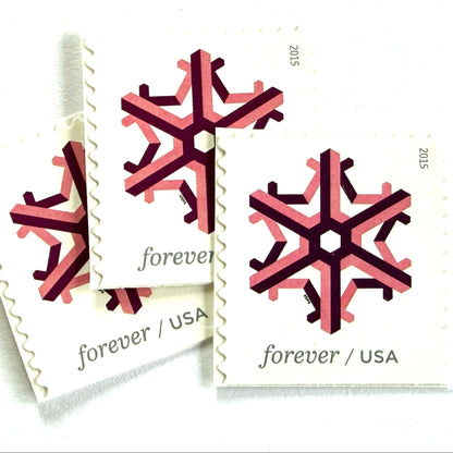 Pink and dark red Geometric Snowflake postage stamps from 2015 featuring a stylized crystalline winter design on unused USPS Forever postage, Scott 5034.