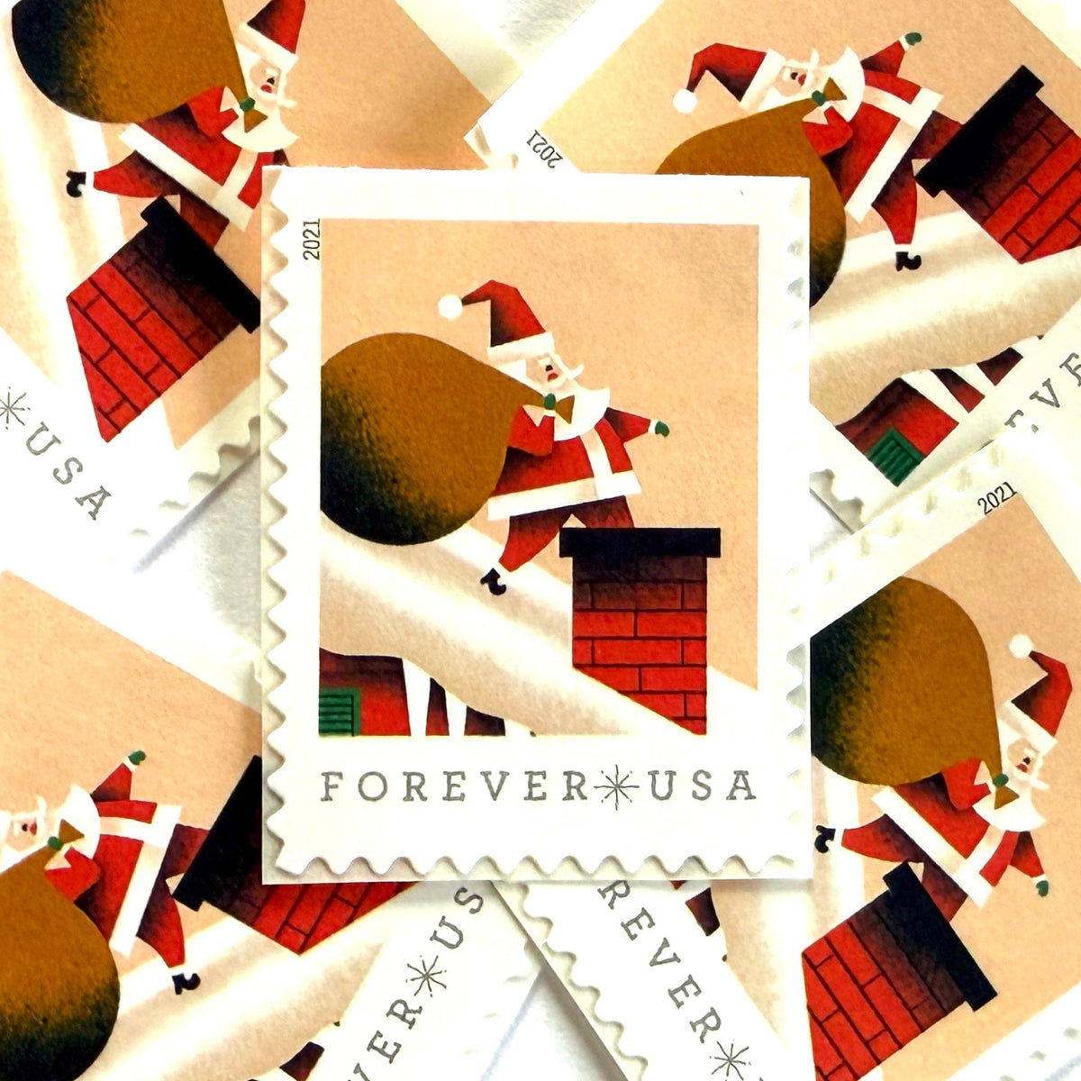 Santa Claus on Roof postage stamps from 2021 featuring St. Nick on a snowy rooftop beneath a pink star-filled sky with one leg inside a red-brick chimney on unused USPS Forever postage, Scott 5644.
