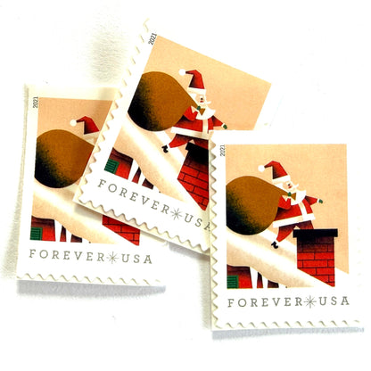 Santa Claus on Roof postage stamps from 2021 featuring St. Nick on a snowy rooftop beneath a pink star-filled sky with one leg inside a red-brick chimney on unused USPS Forever postage, Scott 5644.