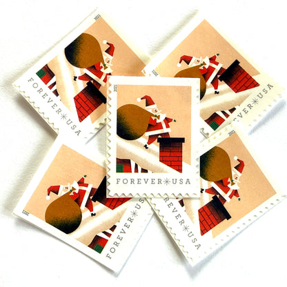 Santa Claus on Roof postage stamps from 2021 featuring St. Nick on a snowy rooftop beneath a pink star-filled sky with one leg inside a red-brick chimney on unused USPS Forever postage, Scott 5644.