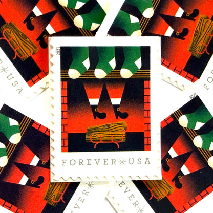 Santa Descending Chimney postage stamps from 2021 featuring St. Nick’s black-booted legs above a red-brick fireplace with green stockings on unused USPS Forever postage, Scott 5645.