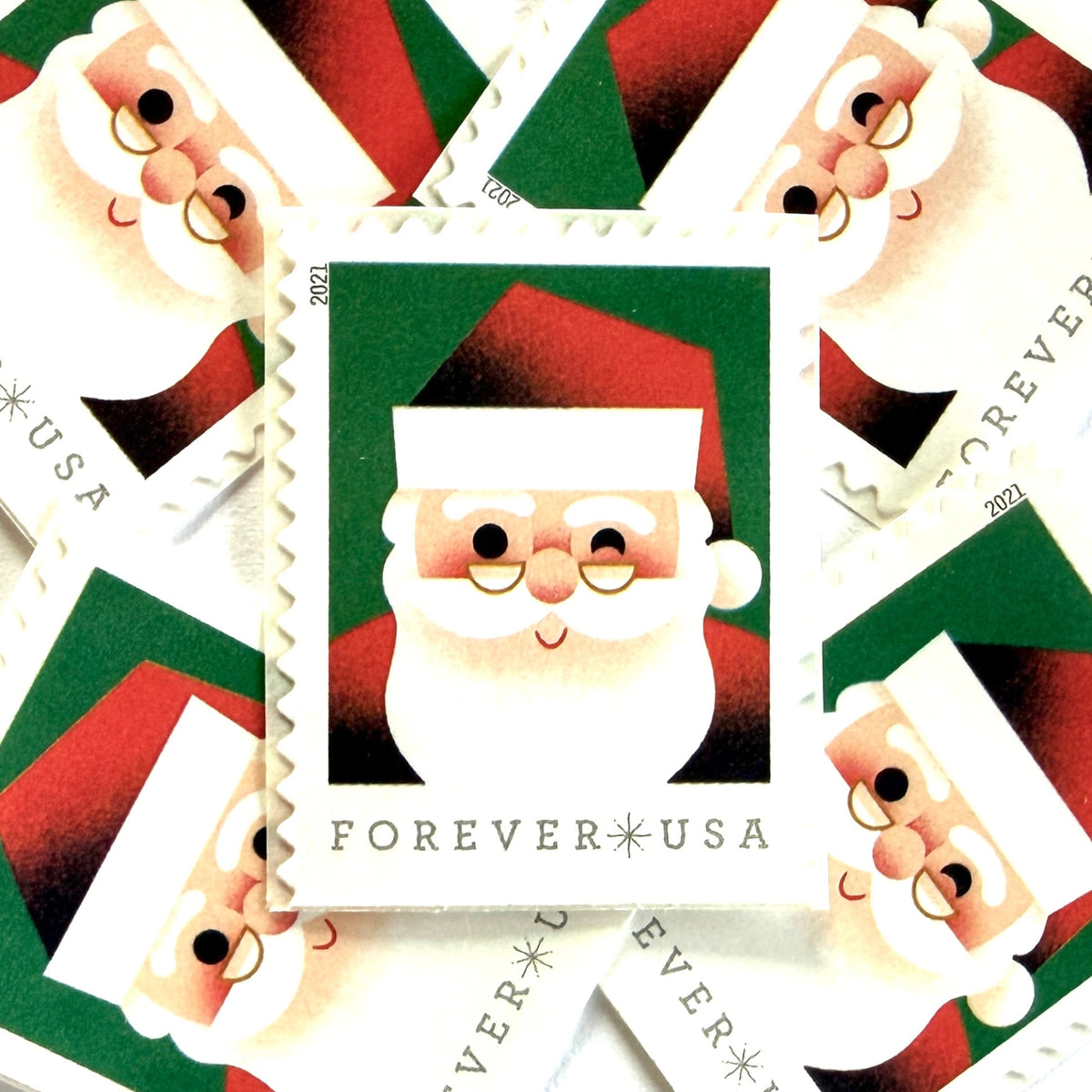Head of Santa Claus postage stamps from 2021 featuring a close-up of a smiling, winking St. Nick against a green background on unused USPS Forever postage, Scott 5646.