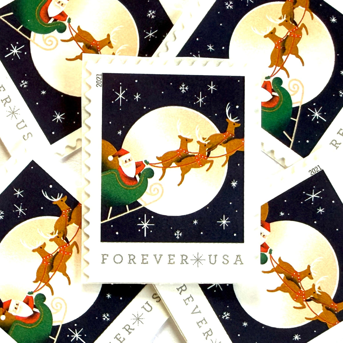 Santa Claus, Sleigh, and Reindeer in Flight postage stamps from 2021 featuring St. Nick and four reindeer flying across a full moon in a dark star-filled sky on unused USPS Forever postage, Scott 5647.