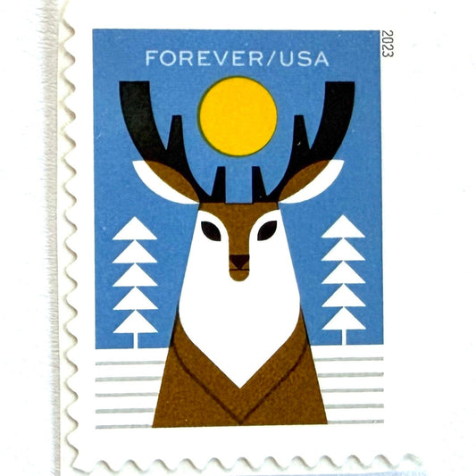 Deer postage stamp from 2023 featuring a stylized woodland deer among snow-covered trees beneath a winter moon on unused USPS Forever postage, Scott 5822.