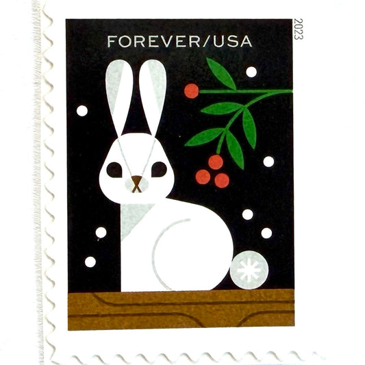 Rabbit postage stamp from 2023 featuring a white woodland rabbit with holly branches and berries in a stylized winter setting on unused USPS Forever postage, Scott 5823.