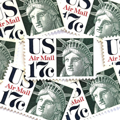 Image of 17-cent Airmail 1983 Liberty Crown USPS postage stamp featuring the Statue of Liberty. Scott #C80. Stamp themes: State of Liberty, Liberty Head, Lady Liberty, New York, NYC, Big Apple, Liberty Island, Immigrants, Immigration, Hope, Freedom, Refuge, Democracy, Crown, Torch, Tablet, Landmark, National Monument, United States of America. Green postage stamp.