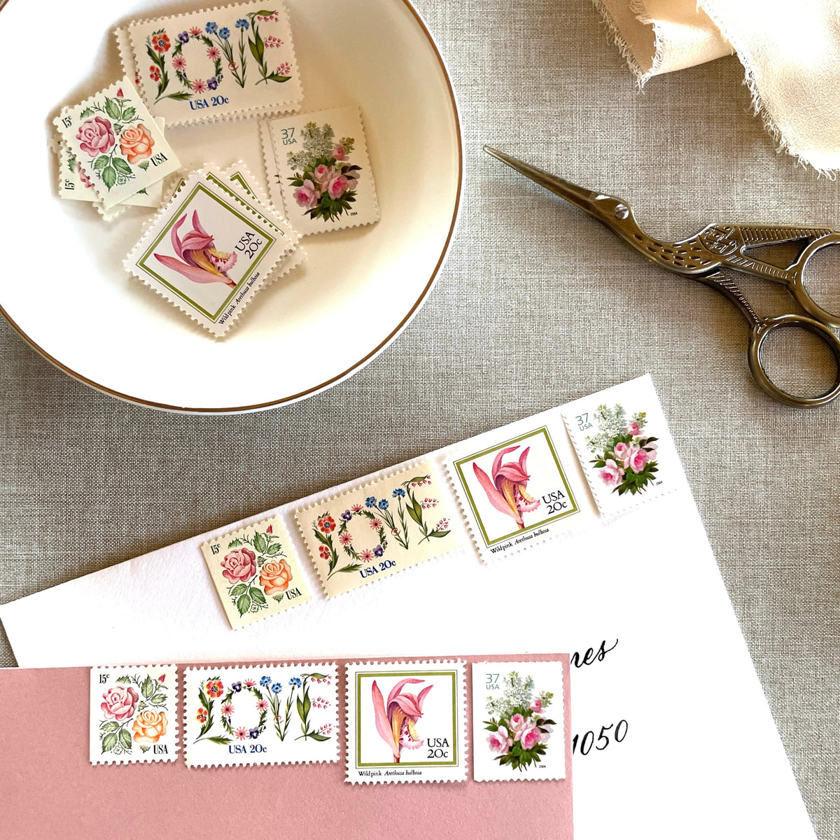 Image of four unused vintage stamps curated and arranged in a USPS postage stamp set for mailing floral and love-themed save-the-dates, wedding invitations, bridal shower invitations, and other special correspondence. This postage stamp set is called the “Pink Floral Love” set, is botanically themed, with pink as the predominant color. The total face value of the set is 92-cents USD.