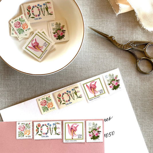 Image of four unused vintage stamps curated and arranged in a USPS postage stamp set for mailing floral and love-themed save-the-dates, wedding invitations, bridal shower invitations, and other special correspondence. This postage stamp set is called the “Pink Floral Love” set, is botanically themed, with pink as the predominant color. The total face value of the set is 92-cents USD.